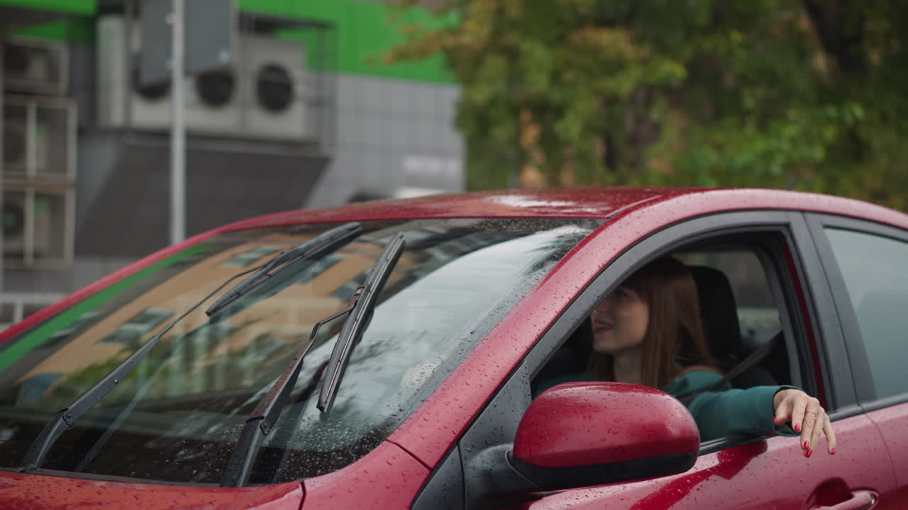 Signora guida l'auto con i tergicristalli che puliscono il parabrezza in una giornata piovosa