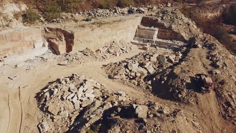workers with professional equipment are working in the sandy quarry on the background of huge stones and a hill with trees. camera motion up