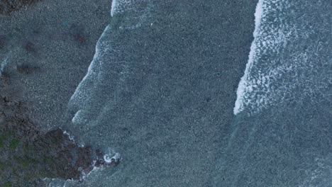 Drone-De-Arriba-Hacia-Abajo-De-La-Acción-De-Las-Olas-Durante-La-Marea-Baja-Sobre-Arrecifes-De-Coral-Y-Rocas-En-La-Playa-De-Nyang-Nyang,-Bali,-Uluwatu,-Indonesia