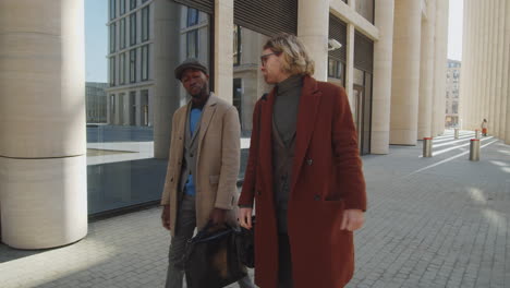 two stylish diverse businessmen walking outdoors and talking