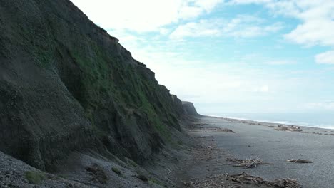 Low-aerial-view-of-coastal-cliffs-meeting-stony-beach-and-ocean---Hakatere-Beach-Alluvial-Cliffs---New-Zealand