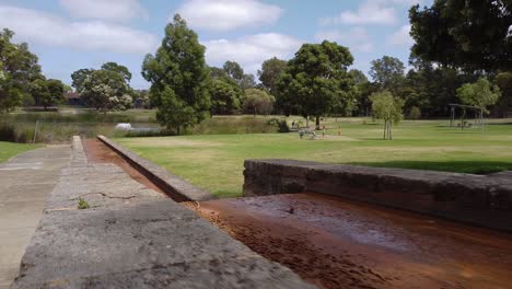 Handheld-Clip-Walking-Alongside-Water-Spillway-Running-Into-Catchment-Lake