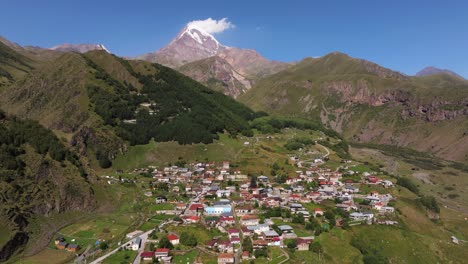 drone disparado hacia adelante sobre gergeti, aldea montañosa georgiana