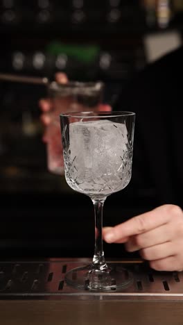 preparing a pink cocktail at a bar