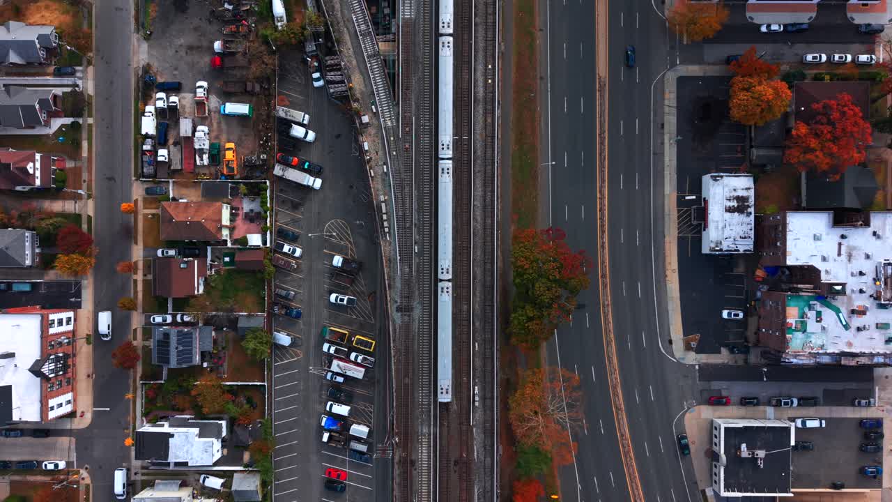 A top down, aerial view of Sunrise Highway running parallel to the Long Island Railroad's elevated train tracks as a train passes by. Taken on Long Island on a cloudy day