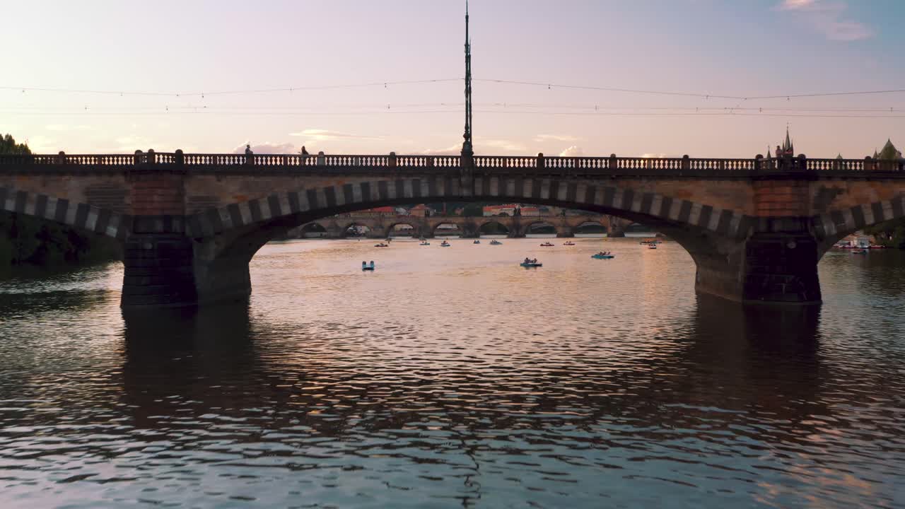Prague sensational aerial view of Vltava river at sunset, drone flying under Legion Bridge then rising revealing beautiful capital cityscape, Czech Republic