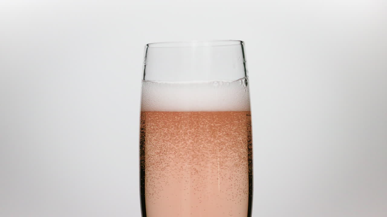 Bollicine macro di vino rosato spumante che si dissipano al rallentatore su sfondo bianco