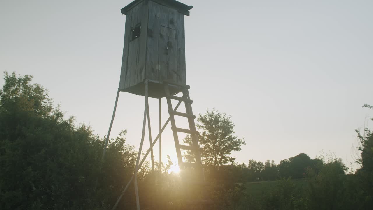 Ripresa grandangolare a mano libera di un'altana da caccia al tramonto con controluce del sole.