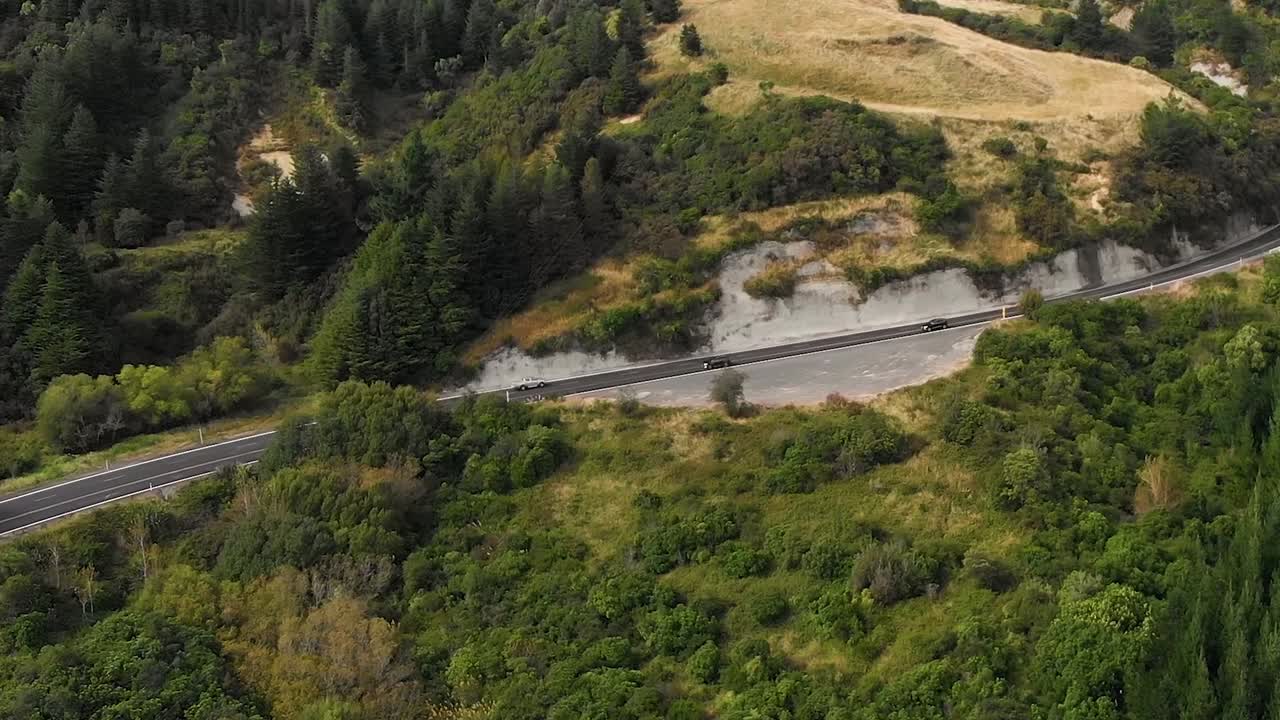 로드 트립 여행에서 자동차를 따라가는 영화 같은 공중 드론, 고속도로에서 운전, 나무로 뒤덮인 산 언덕 주변, 도로에서 다른 차량 추월