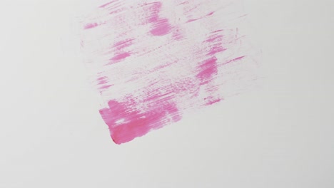 Close-up-of-pink-paint-shapes-on-white-background-with-copy-space,-slow-motion