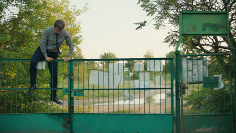 man climbing/standing by a gate in a park