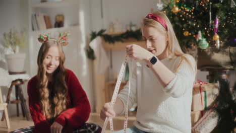 Beautiful-woman-wrapping-Christmas-gifts-with-sister-at-home