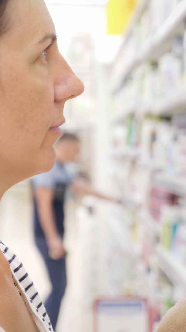 Woman examining cosmetic product in a store aisle with colorful packaging in the background