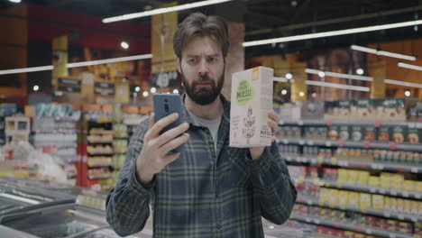 man shopping at the grocery store and looking at his phone