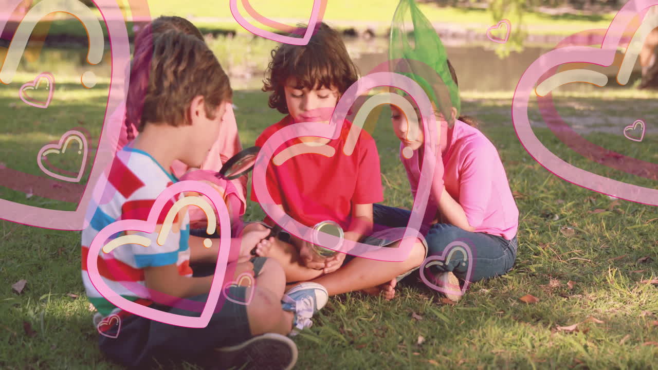 Children sitting on grass examining objects with heart animations overlay