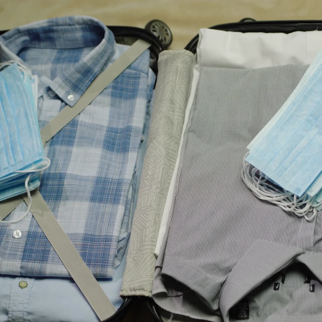 el hombre pone ropa, máscaras protectoras y antiséptico en una maleta 2