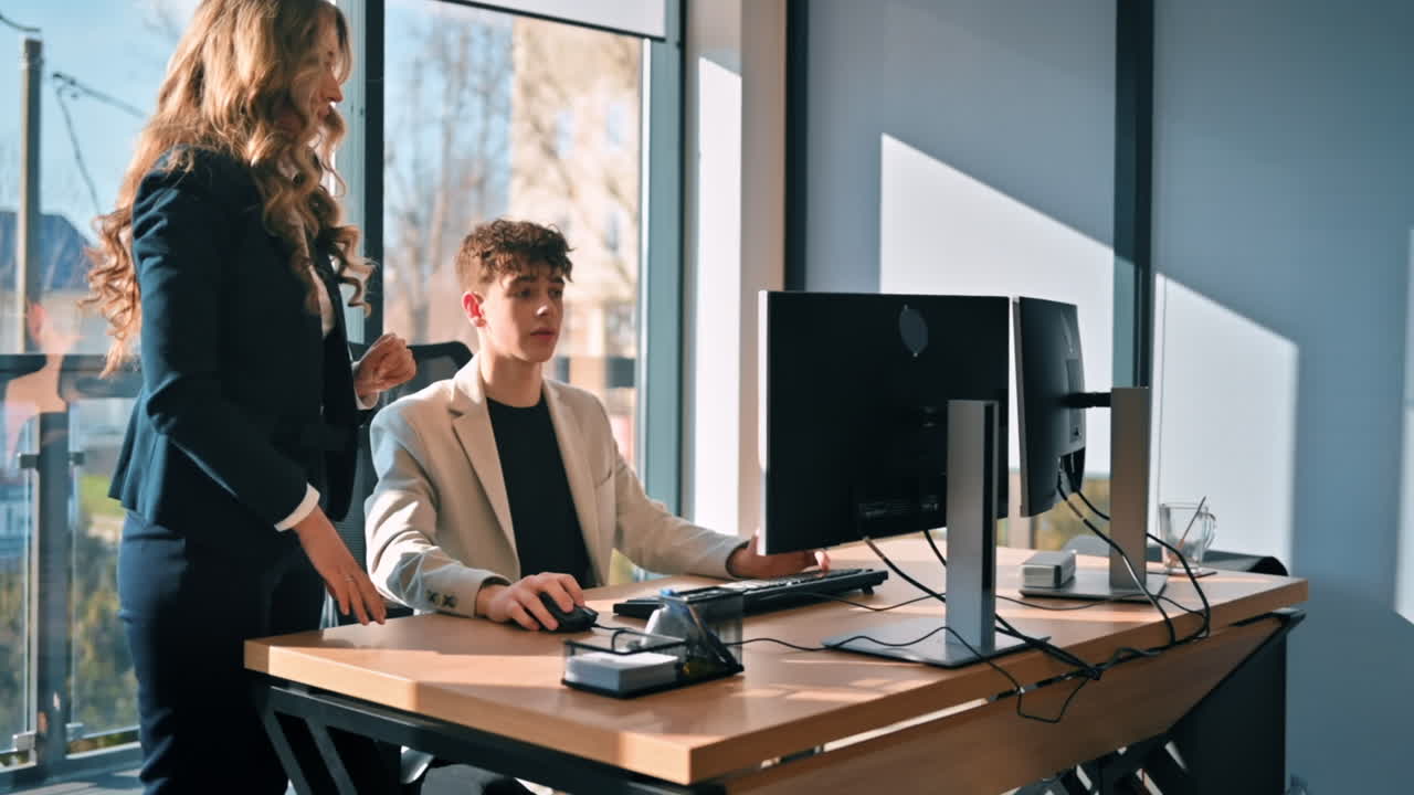 Sessione di lavoro in un ufficio. Un giovane sta usando il computer e discutendo di affari. Rallentatore