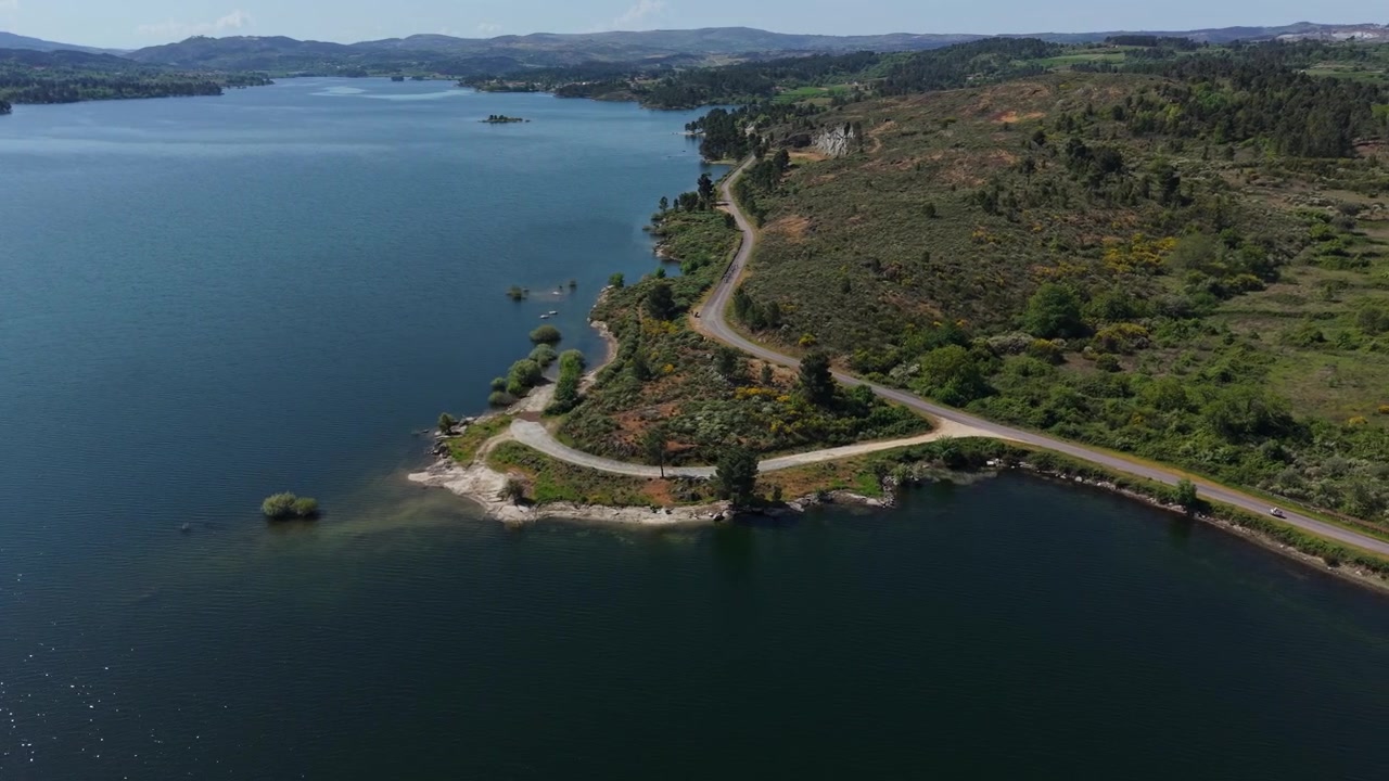 Una strada tortuosa si snoda lungo la vasta costa della macchia del bacino del Douro con isole rocciose e colline distanti
