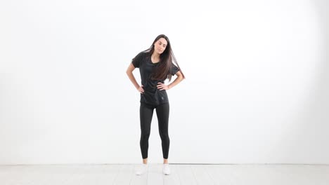 young woman in black athletic wear posing against a white background