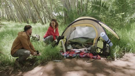 Happy-african-american-couple-pitching-tent-in-forest,-slow-motion