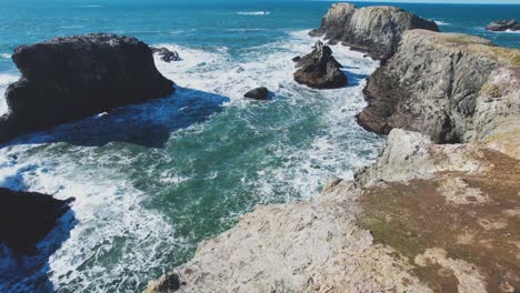 Startled-seagulls-soar-above-Bandon-oregon-coast-as-waves-crash-against-sea-cliffs