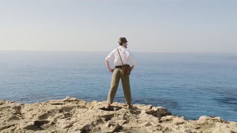 man looking at the ocean from a cliff