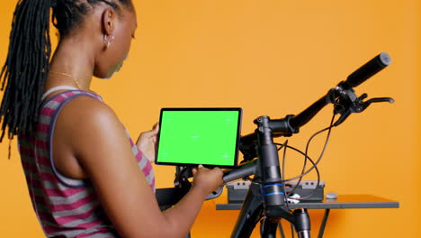 joyful woman following tutorial videos on mockup tablet, learning to mend bike