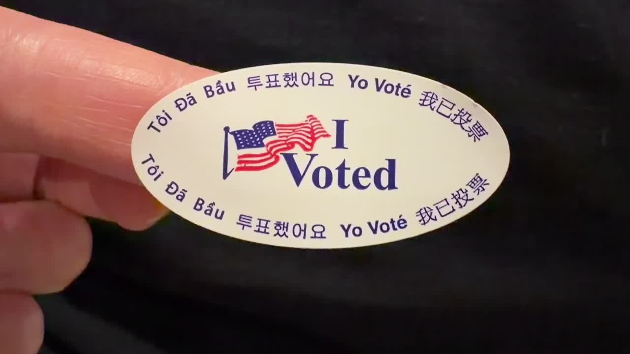 Finger holding up a "I Voted" sticker translated in different languages. 2025 Special Elections in California, USA