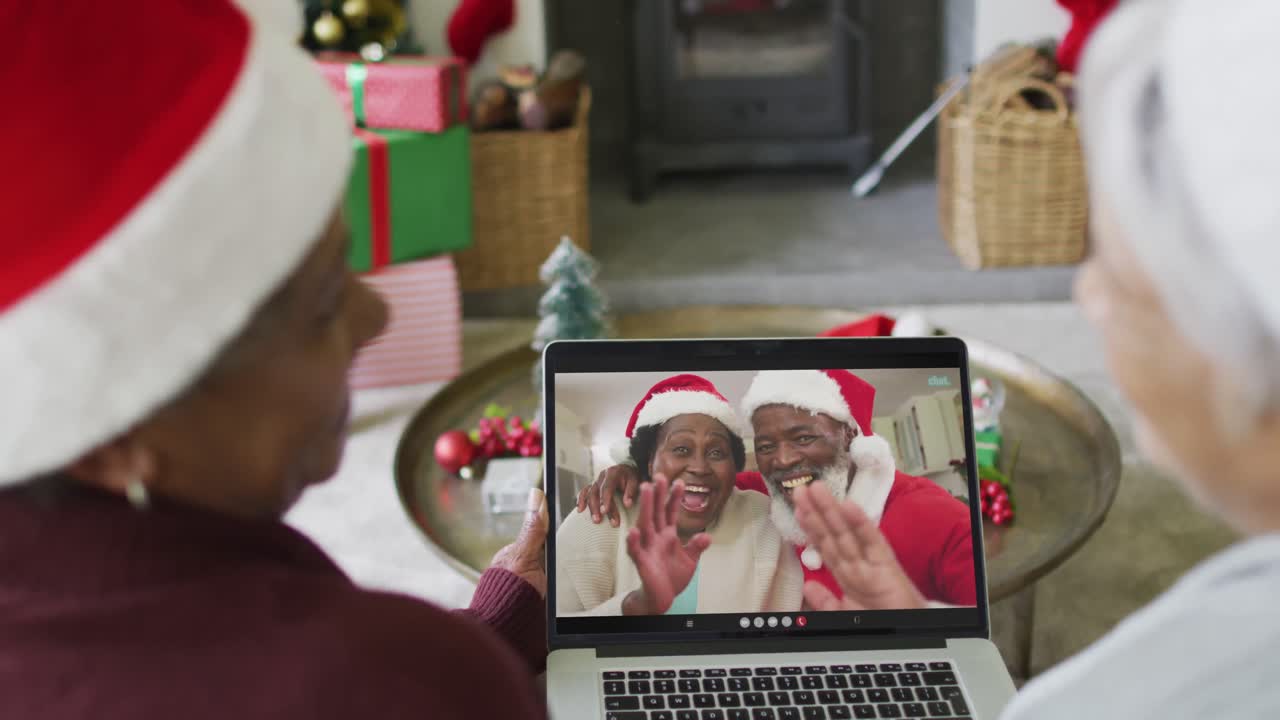 diversas amigas mayores que usan una computadora portátil para una videollamada de navidad con una pareja feliz en la pantalla