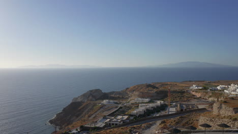 aerial: backwards reveal, drone passes very close to windmills in oia of santorini, greece