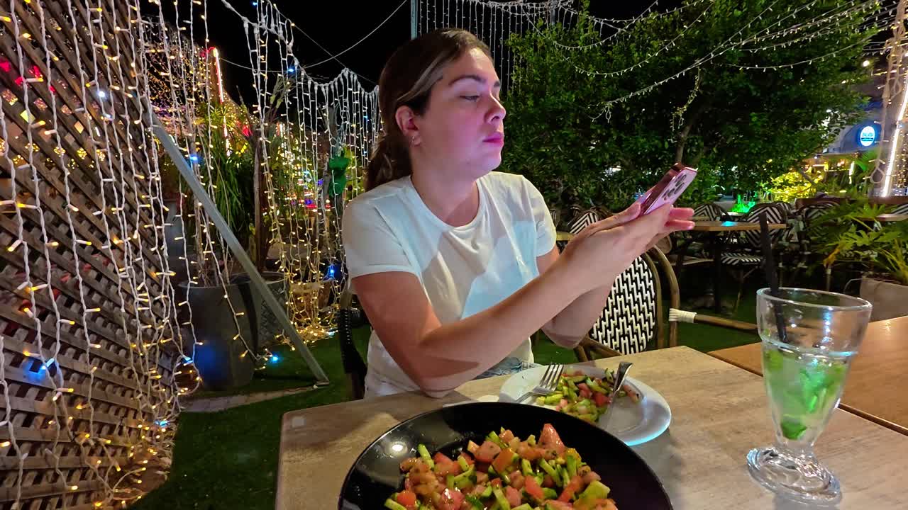 Woman Talking on Speakerphone While Dining at a Restaurant