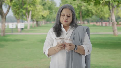 serious indian mother counting money in park