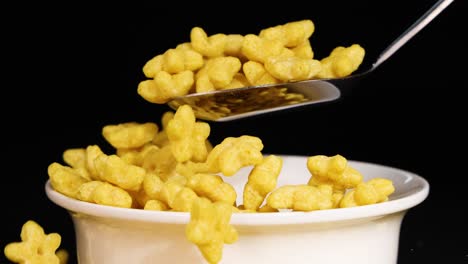 star-shaped cereal in a bowl with spoon interaction against a black background, highlighting texture and movement
