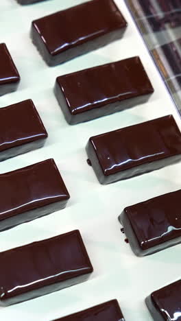 manufacture of chocolate bars. ready-made candies move along the conveyor belt. sweet desserts enterprise. close up. vertical video