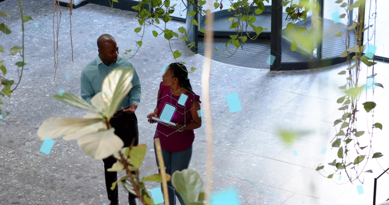 Coworkers entering revolving door and analyzing tech data on tablet with floating blue charts