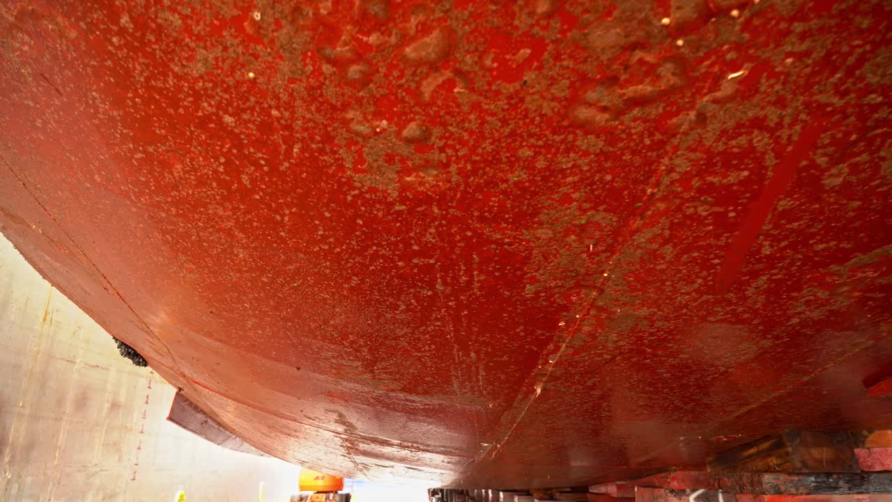 드라이독 내부에서 본 배 바닥 아래의 더러운 배 선체 - 연료 소비 및 효율성에 영향을 미치는 먼지 - 청소를 위한 도킹