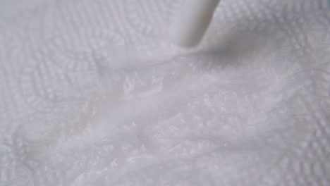 spraying liquid from white plastic tube onto paper napkin