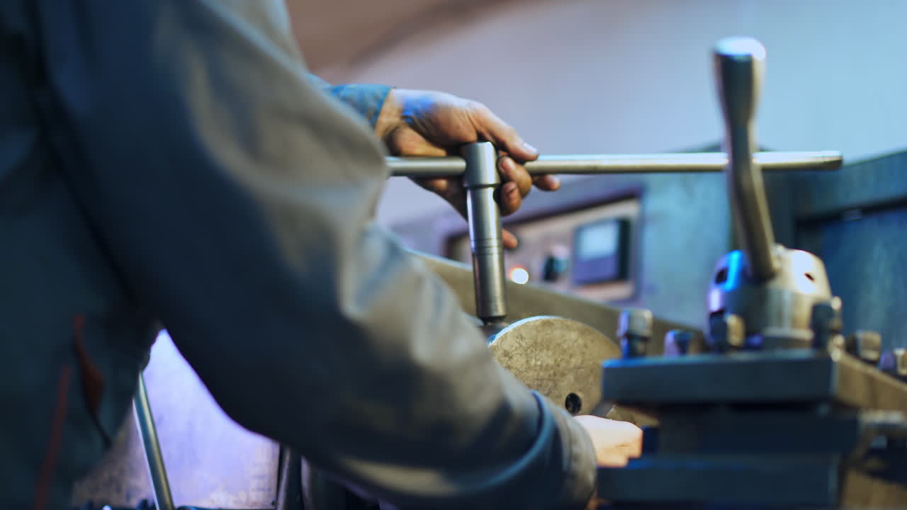 Hands of a turner applying lathe wrench. Man tuning turning lathe to work. Close up.