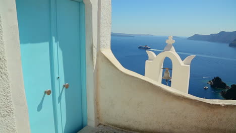 un crucero a lo lejos detrás de una iglesia de una isla griega con una puerta azul