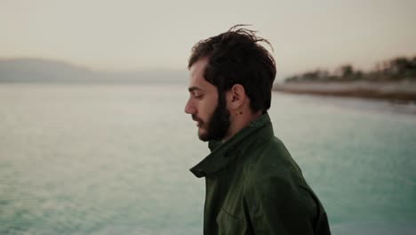 Profile-view-of-grieving-bearded-man-walking-on-edge-of-Dead-Sea,-Israel