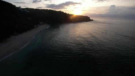 scenic beach in bali coastline during the sunset, silhouette of forested hillside
