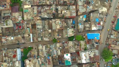 cars driving on the street with rooftops of crowded residential buildings in new delhi, india.  - aerial