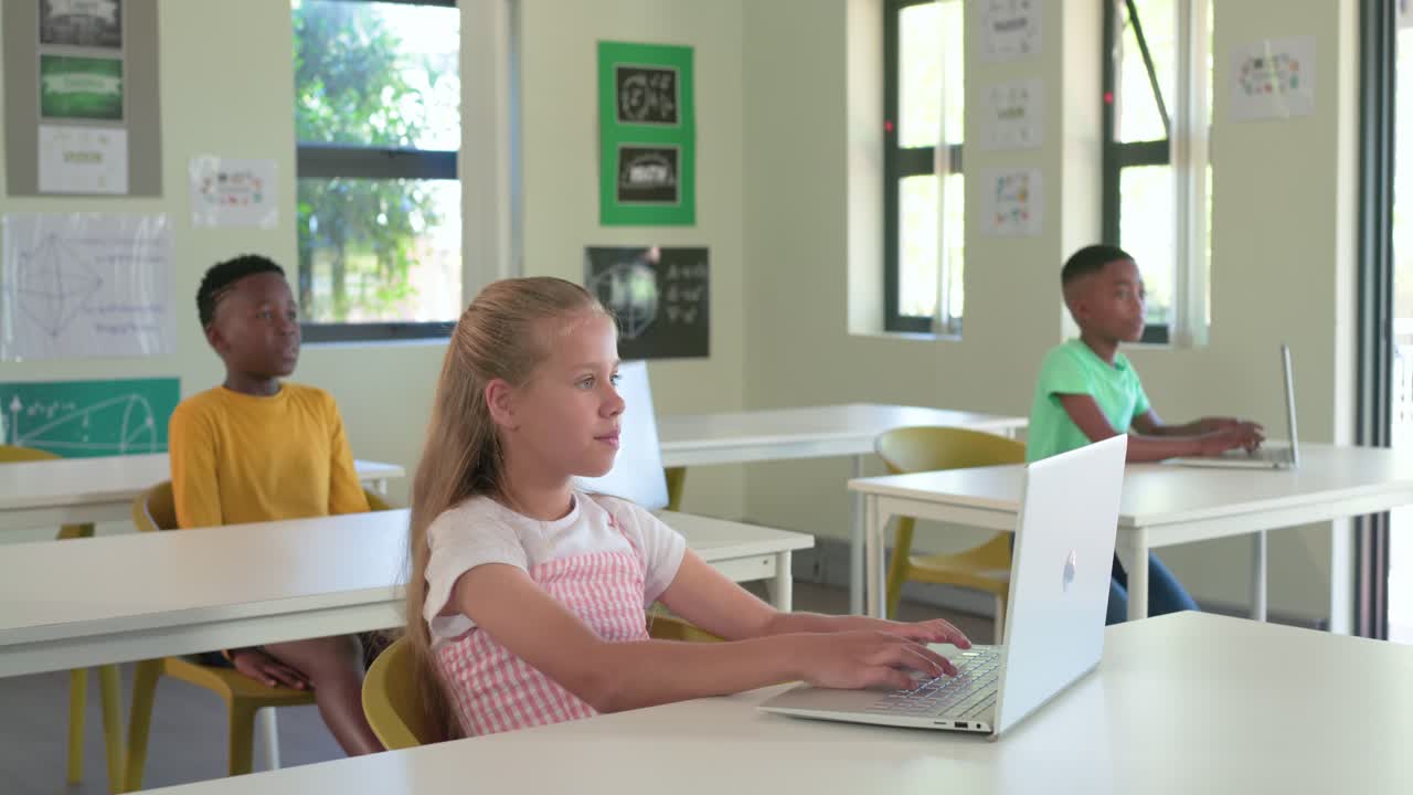 Diverse teen class replying to offframe cue, girl in pink dress typing on laptop, boys reacting