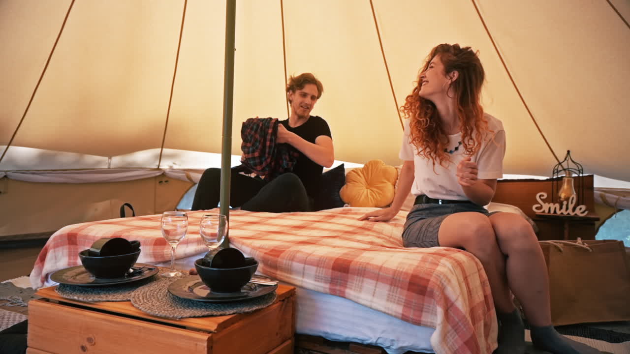 Couple entering the tent and sitting on the bed. Young man and woman. Glamping. Slow motion