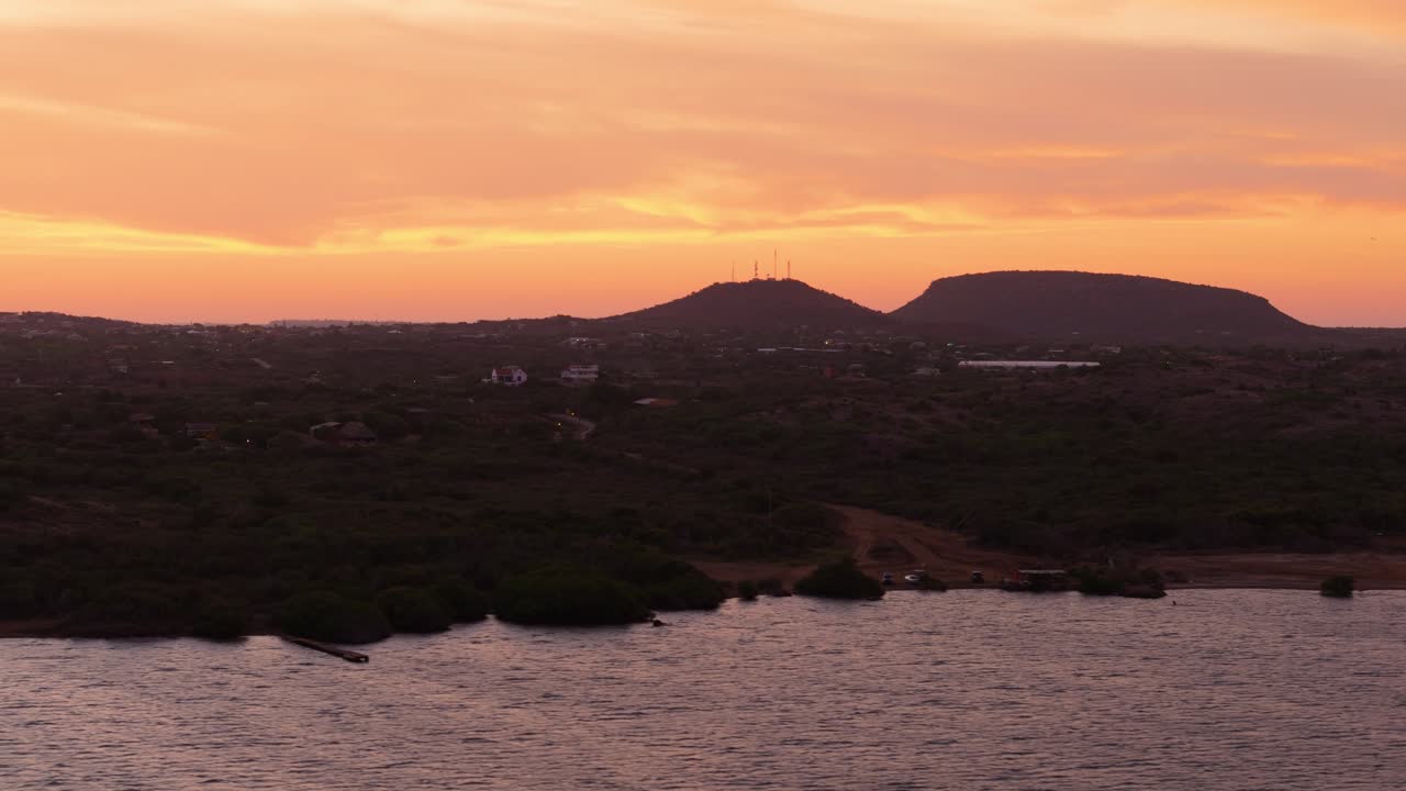 Vista aérea de una costa con la suave luz del sol reflejándose en las tranquilas olas del océano durante el atardecer