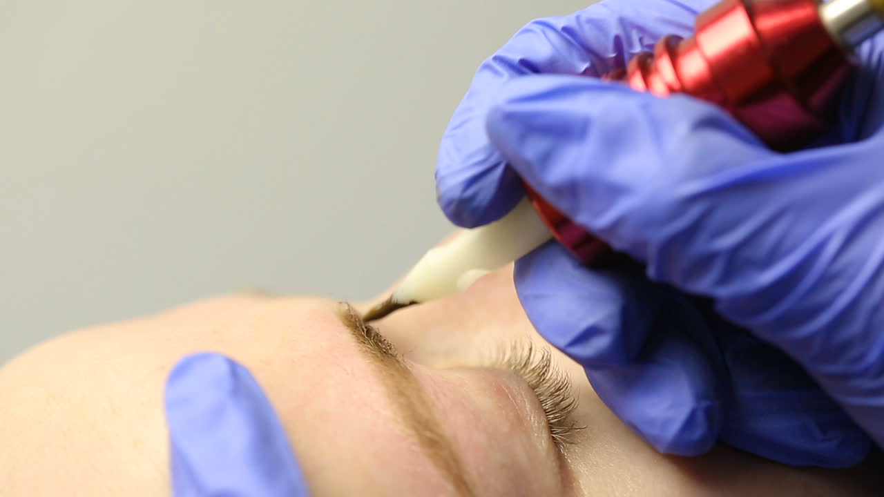 Closeup portrait of lovely young woman getting permanent makeup on her eyebrows