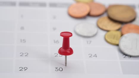 calendar with coins and red pin