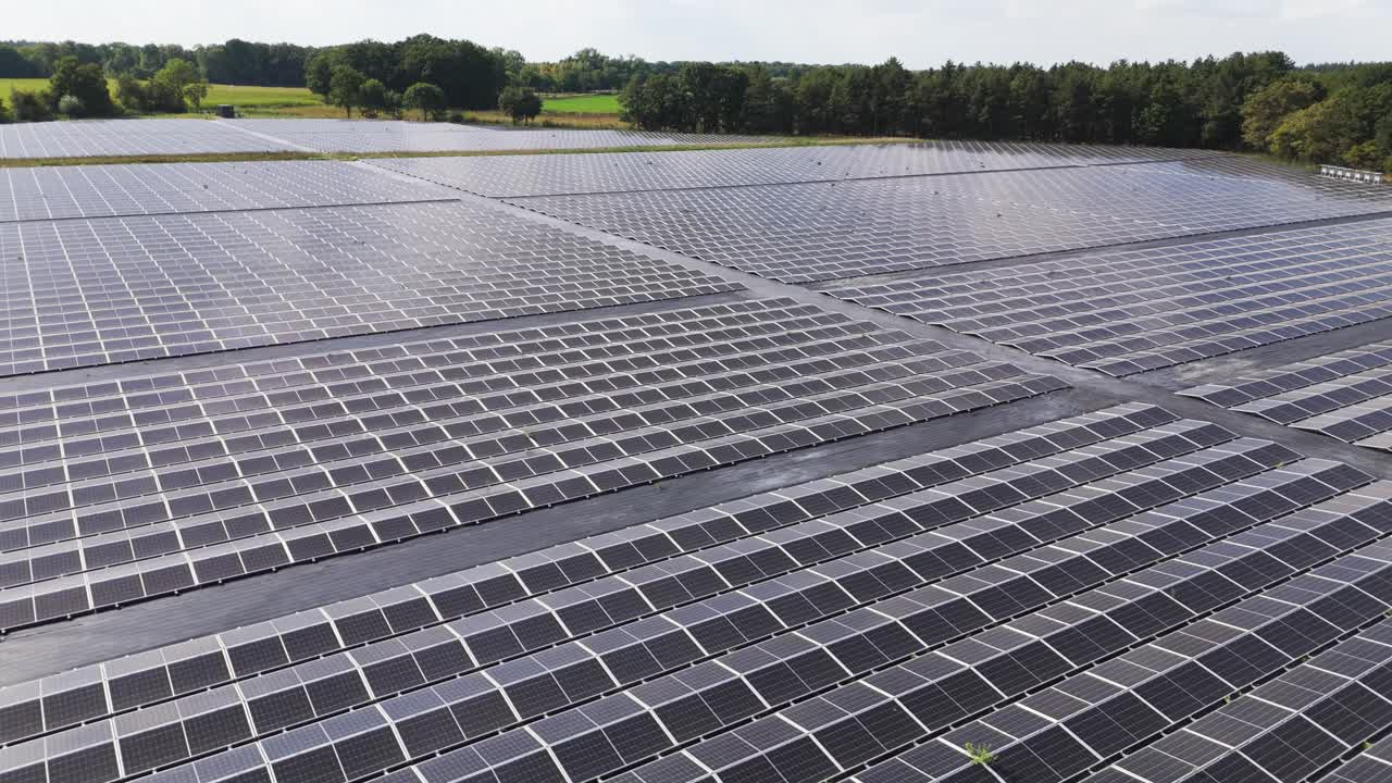 Drone footage flying over a large solar farm with photovoltaic panels in a rural landscape, symbolizing renewable energy, sustainability, and climate change solutions for a greener future