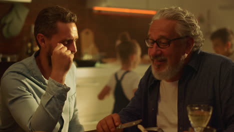 senior father and adult son sitting at dining table