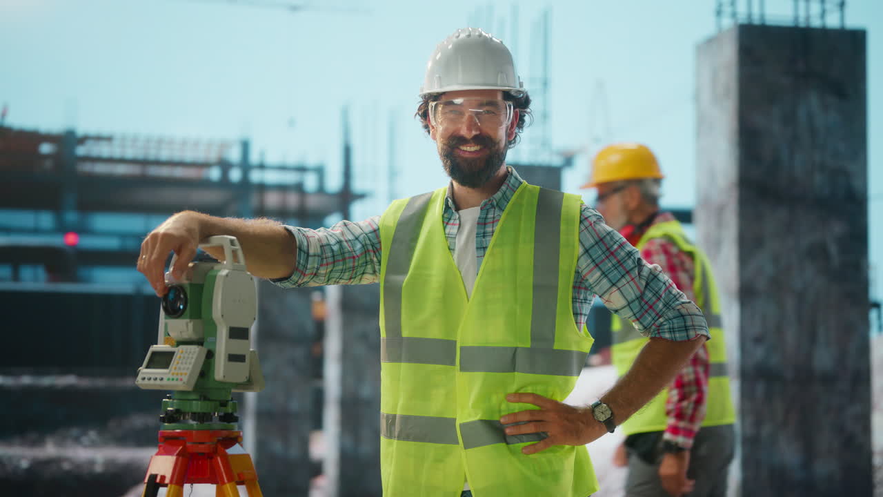 Smiling Male Surveyor Standing Next to Theodolite on a Construction Site